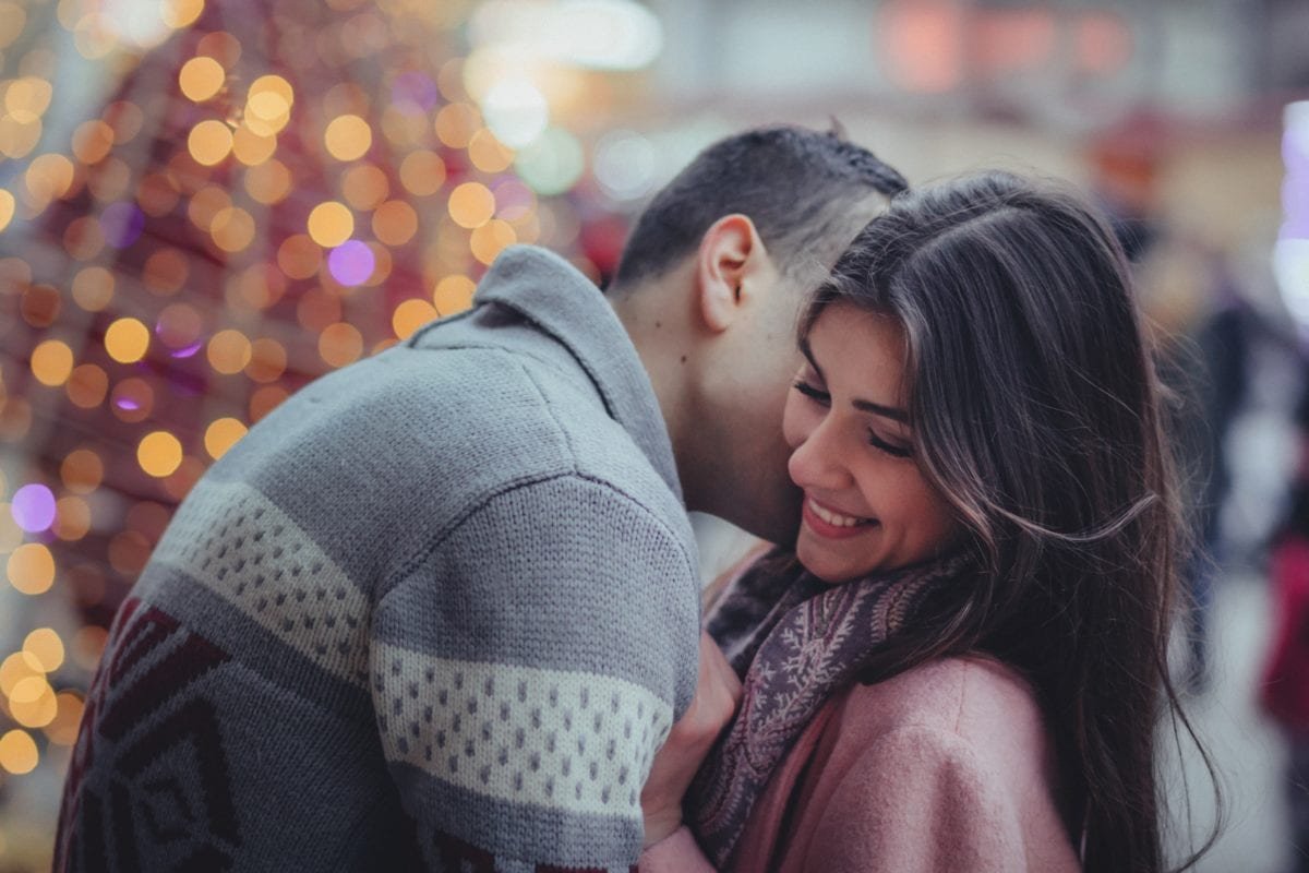 A guy kissing his girlfriend on the neck