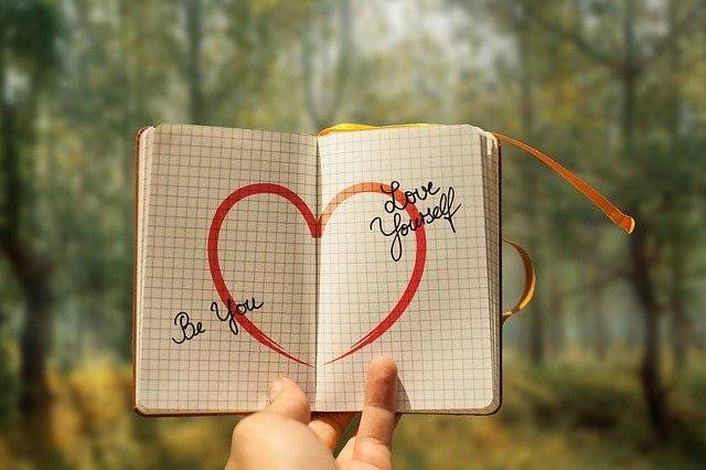 A book with a love sign and words that says be you, love yourself.